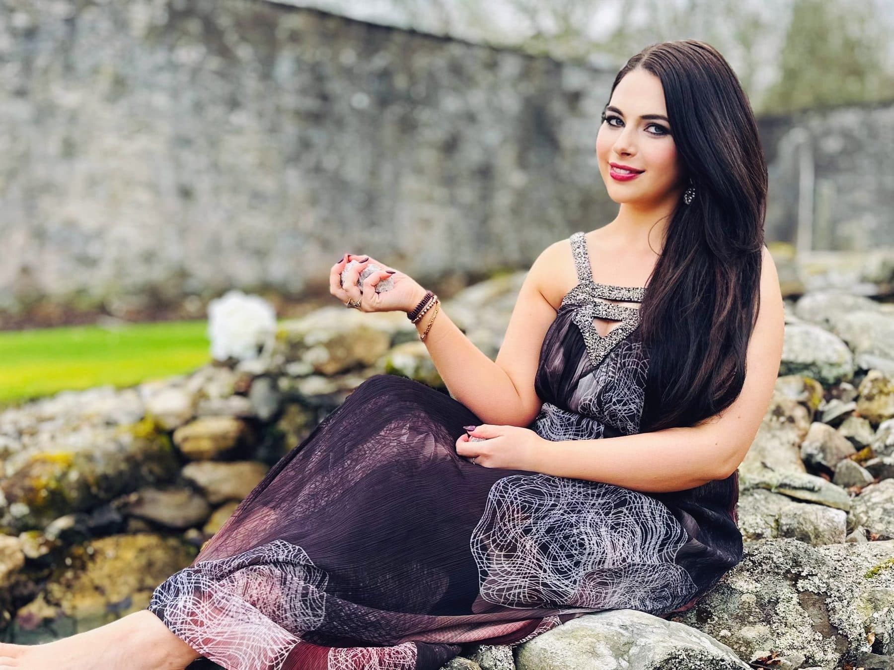 Katherine sitting on the rocks beside a stream, holding crystals